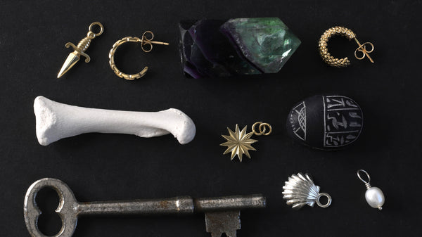 Jewellery items from the Parliament Coven Collection are shown laying on a black and white stone surface.